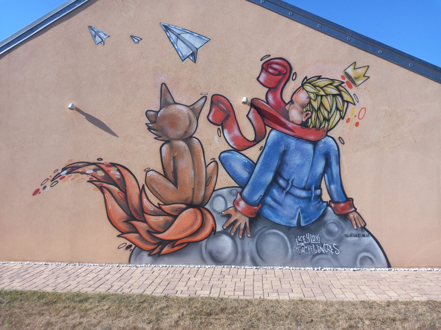 [Justine CM] Danjoutin. Photo prise en août 2022. Streetart avec peint sur une maison Le Petit Prince et le renards, assis sur la Lune en train de regarder des avions en papier voler.